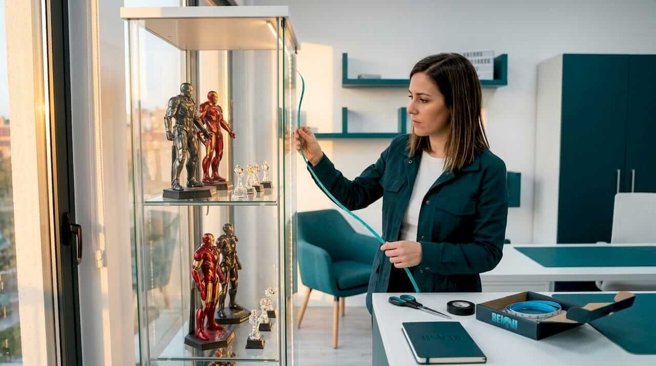 Una mujer le da un toque especial a su colección de figuras instalando luces LED en la vitrina para resaltarlas.
